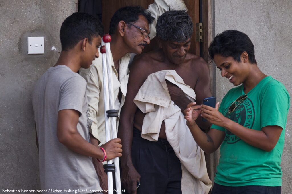 Fishing Cat (Prionailurus viverrinus) biologists, Anya Ratnayaka and Tharindu Bandara, showing fishing cat pictures to wetland neighbors, Urban Fishing Cat Project, Diyasaru Park, Colombo, Sri Lanka